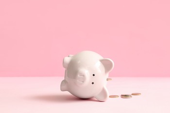 Sparschwein liegt auf der Seite, Münzen daneben
